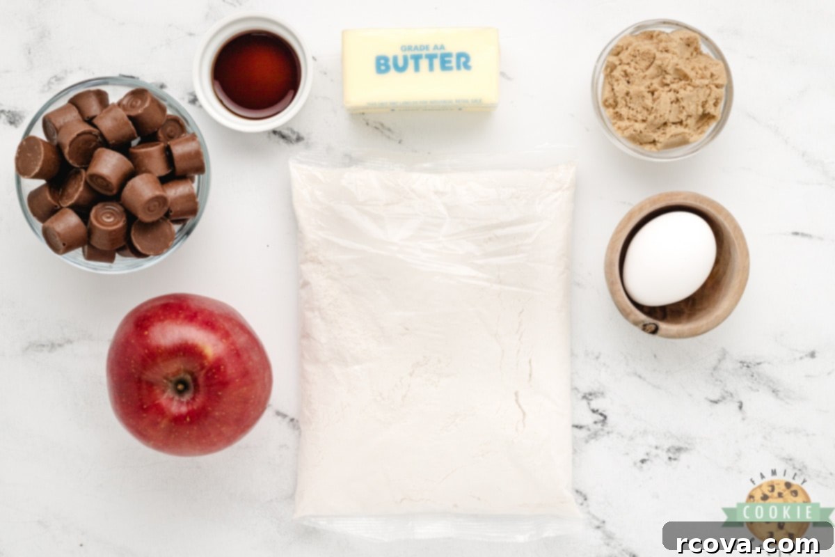 Irresistible Caramel Apple Cake Mix Cookies 6 All the ingredients for Caramel Apple Cake Mix Cookies laid out on a white surface, including cake mix, Rolo candies, butter, brown sugar, egg, vanilla, and a chopped apple.