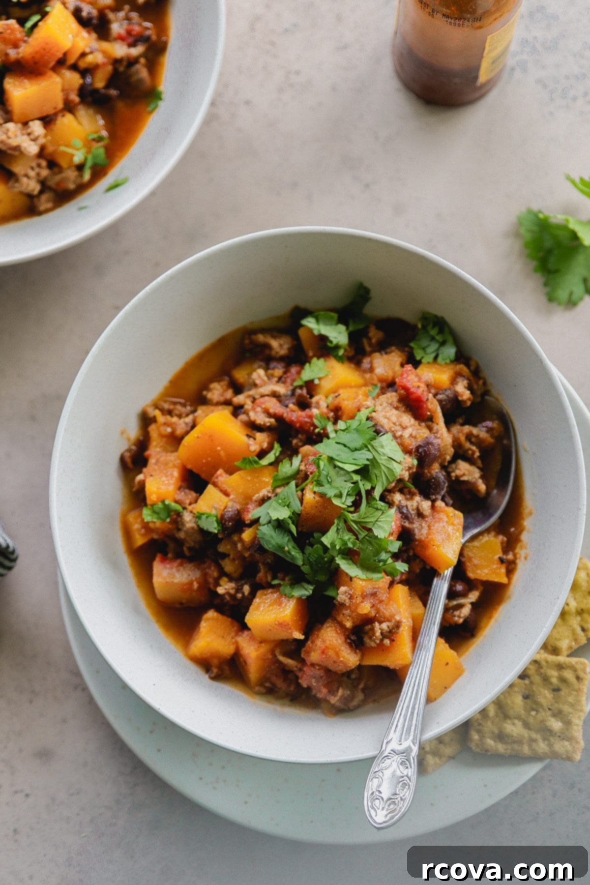 Hearty Butternut Squash Turkey Chili 2 A steaming bowl of healthy butternut squash turkey chili garnished with fresh cilantro.