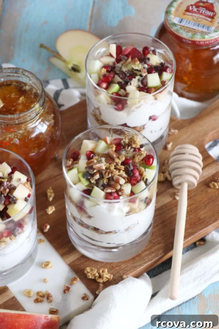 Cozy Winter Parfaits 3 Close-up of a layered winter fruit parfait in a clear glass, showing the creamy Greek yogurt, golden honey, crunchy granola, and vibrant fresh fruit.
