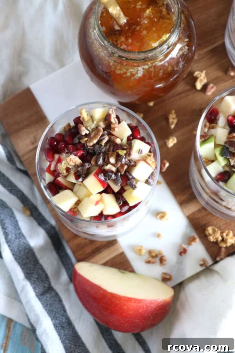 Cozy Winter Parfaits 6 A close-up view of the top layer of a winter fruit parfait, adorned with vibrant pomegranate seeds, apple pieces, and a sprinkle of cacao nibs.