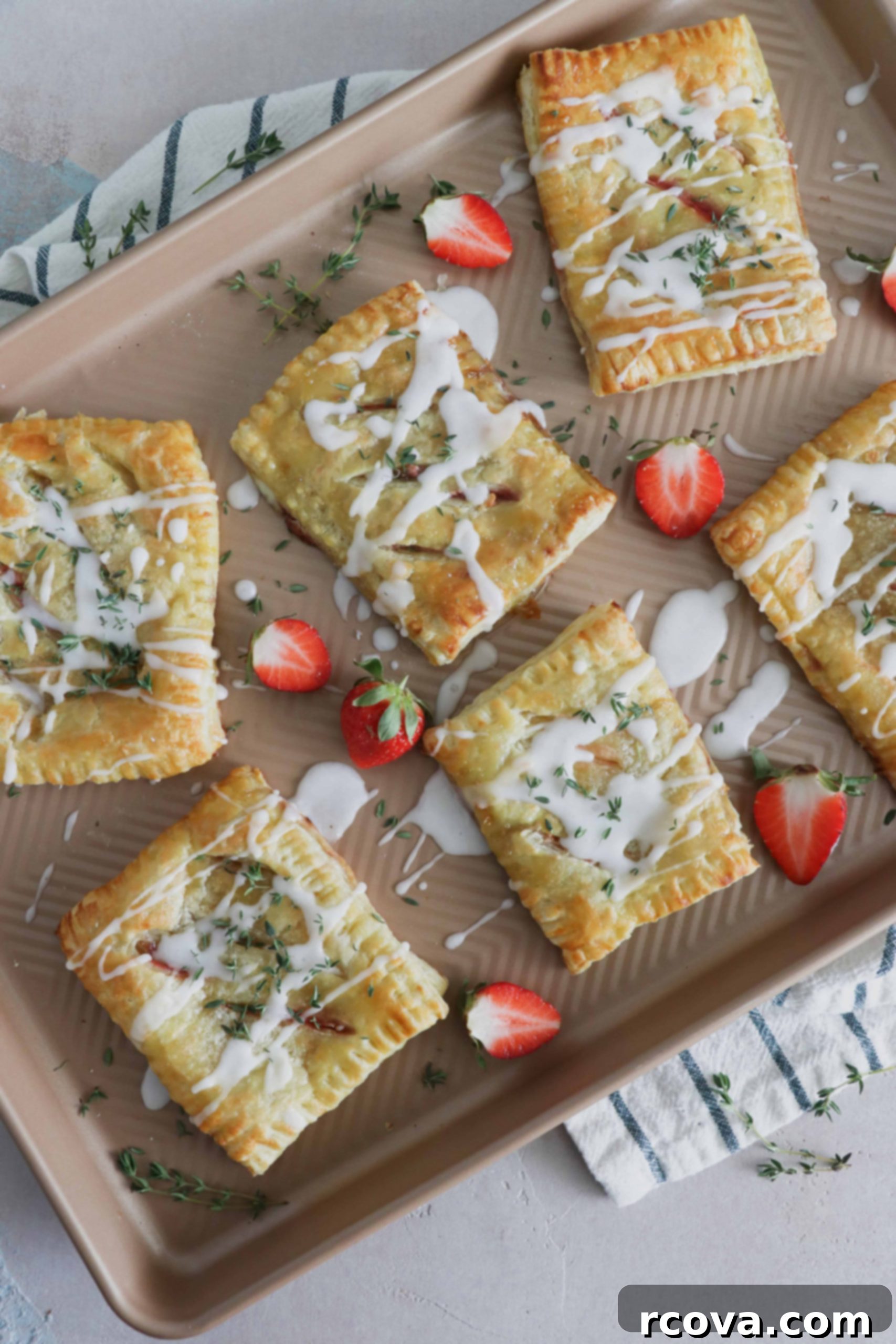 Strawberry Thyme Chevre Pockets 2 Golden brown strawberry, thyme, and goat cheese hand pie with a bite taken out, revealing the red strawberry filling and white goat cheese.