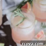 Herbal Grapefruit Gin Sparkler 5 A vibrant Pink Grapefruit Gin Fizz cocktail with cucumber and rosemary garnish.