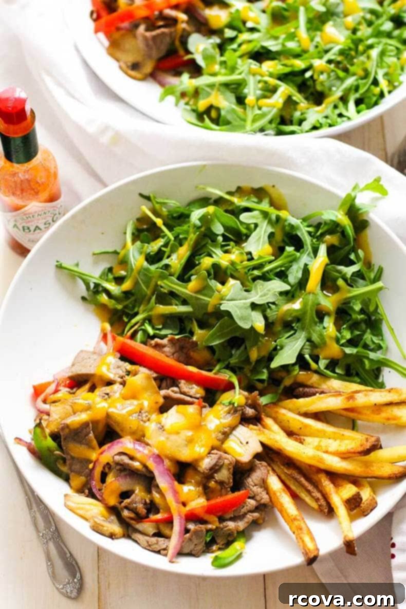 Low Carb Philly Cheesesteak Salad Bowls 4 Close-up of a freshly prepared Philly Cheesesteak Salad Bowl, highlighting the juicy steak, colorful sautéed vegetables, and melted cheddar cheese on a bed of greens.