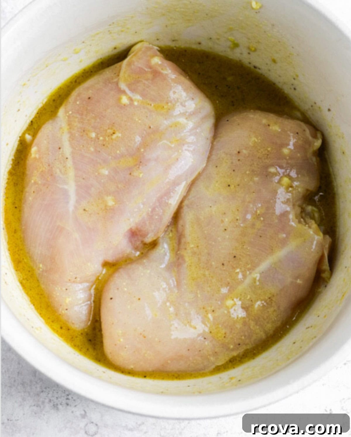 Dijon-Kissed Grilled Chicken & Bacon Salad 5 Raw chicken breast marinating in a vibrant lemon and Dijon mustard dressing in a bowl.