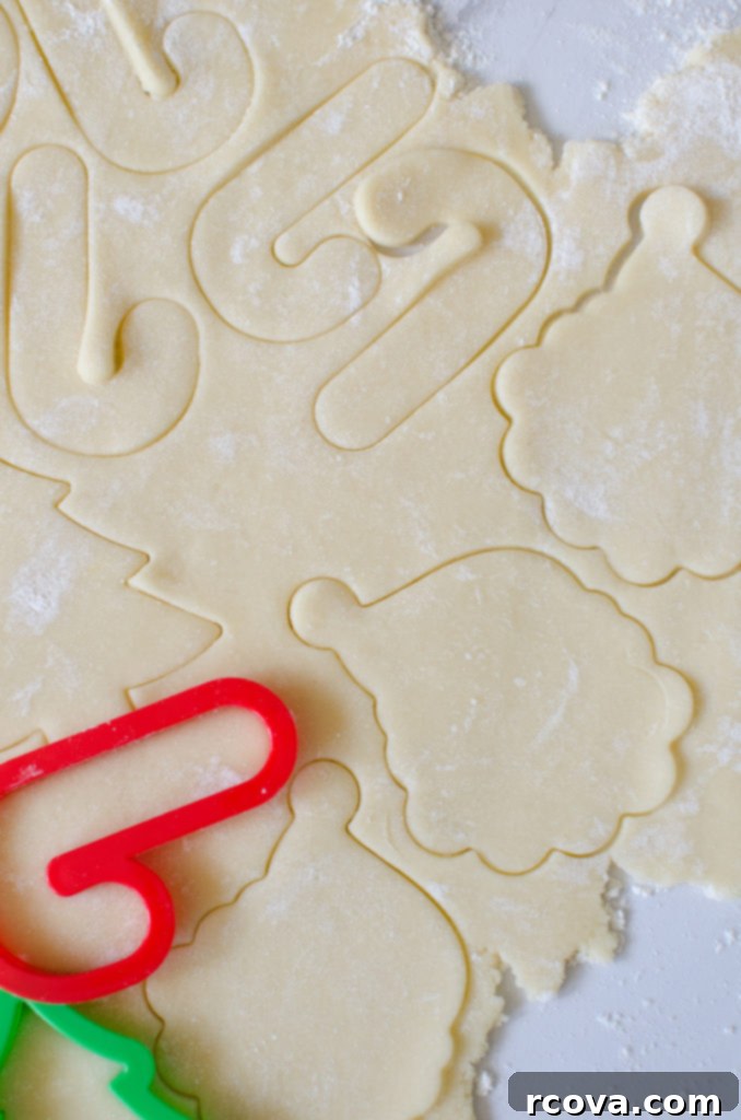 Classic Christmas Sugar Cookie Recipe 4 Three fully decorated Christmas sugar cookies with white and red buttercream frosting and sprinkles.