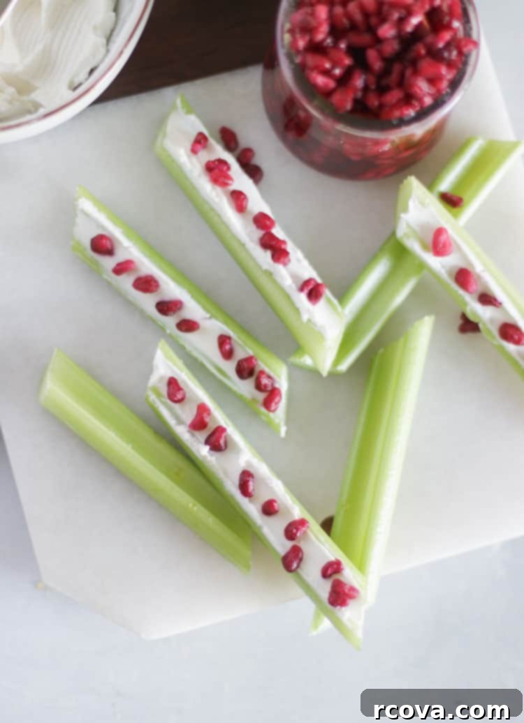 Jeweled Celery Bites with Goat Cheese and Pomegranate 6 Close-up of a single Goat Cheese and Pomegranate Stuffed Celery stick on a white background