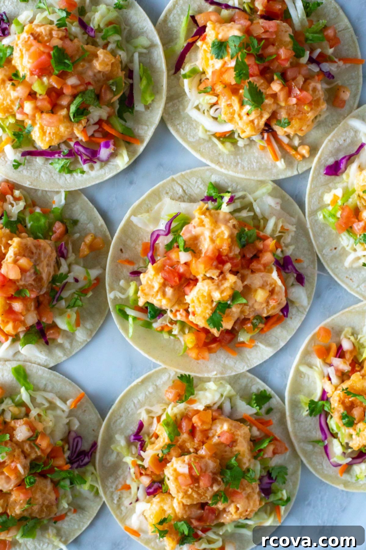 Spicy Bang Bang Shrimp Tacos 2 Overhead shot of assembled bang bang shrimp tacos with fresh cilantro and lime wedges