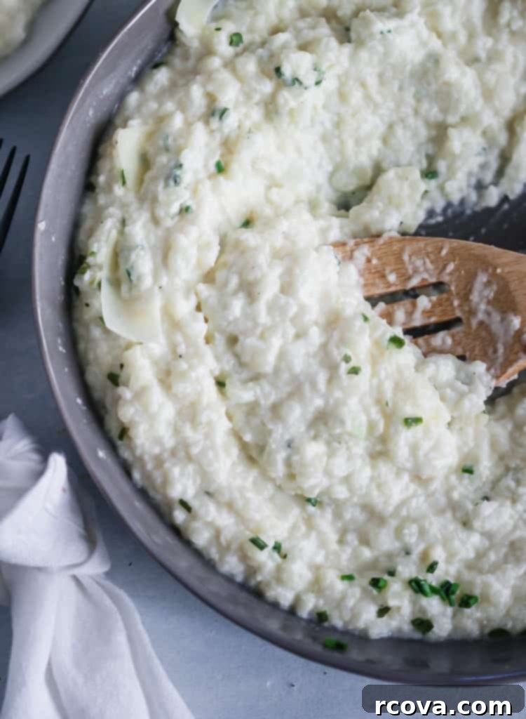 Roasted Garlic Parmesan Cauliflower Cloud 2 Close-up of creamy roasted garlic parmesan mashed cauliflower in a bowl, garnished with fresh parsley.