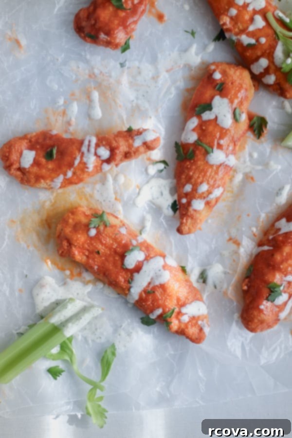 Crispy Air-Fried Gluten-Free Buffalo Tenders 4 Three golden-brown air fryer buffalo chicken tenders drizzled with hot sauce, ready to serve.