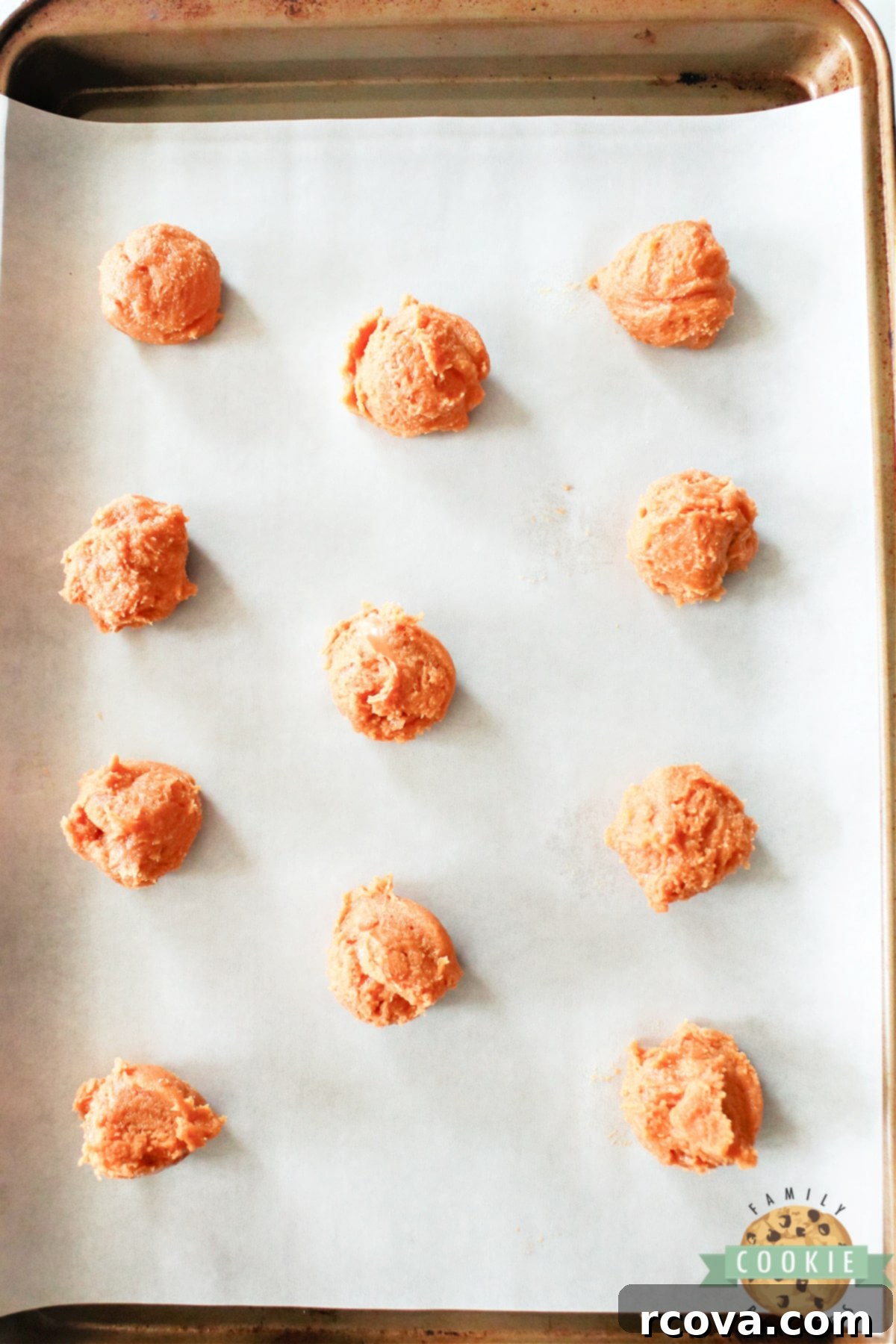Peanut Butter Jelly Cookie Dreams 6 Evenly spaced scoops of raw peanut butter cookie dough arranged on a parchment-lined baking sheet, ready for the next step.