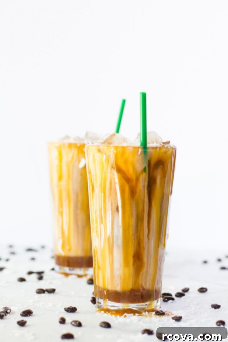 Tropical Salted Caramel Iced Macchiato 2 Two glasses of homemade Iced Coconut Milk Caramel Macchiatos garnished with coconut flakes and caramel drizzle.