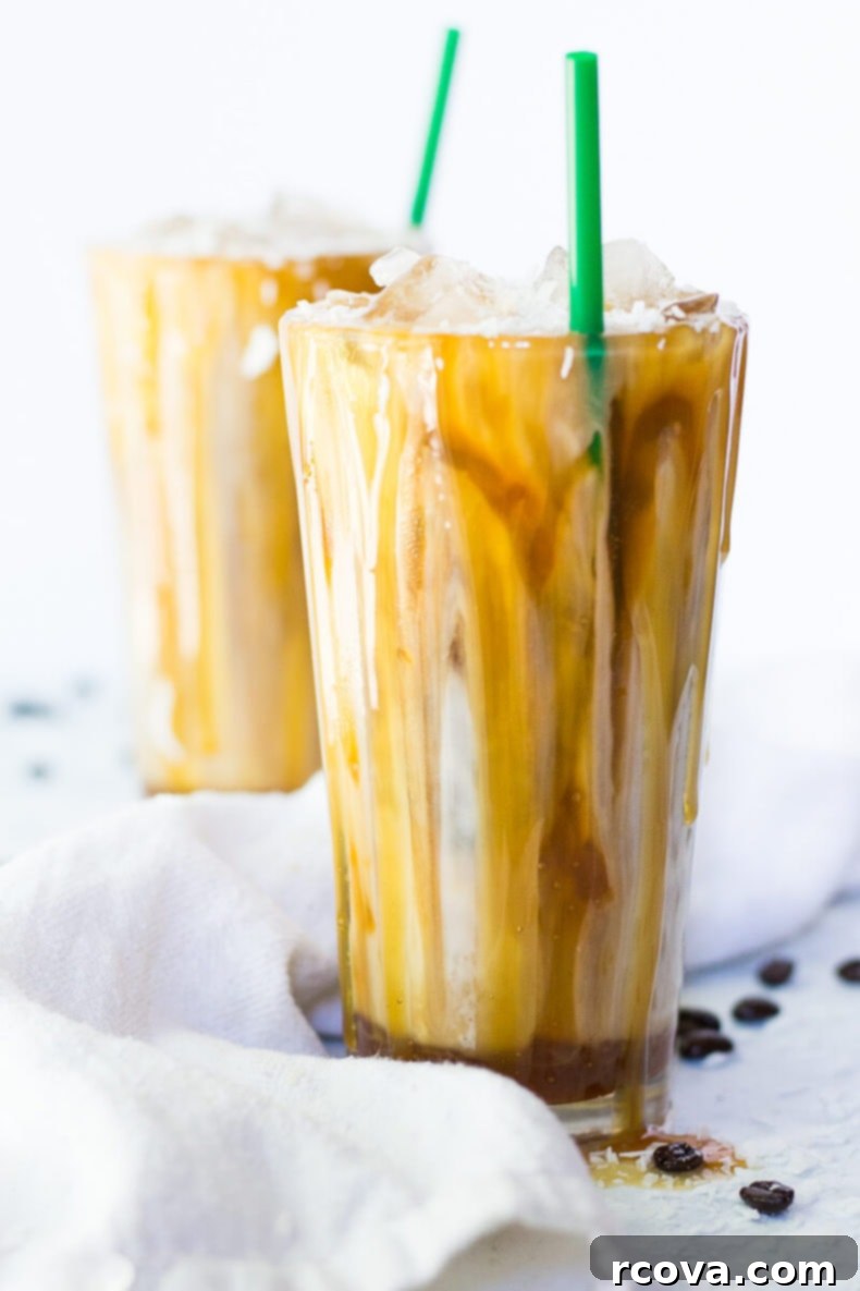 Tropical Salted Caramel Iced Macchiato 6 Two hands holding Iced Coconut Milk Caramel Macchiatos, showing the layered effect.