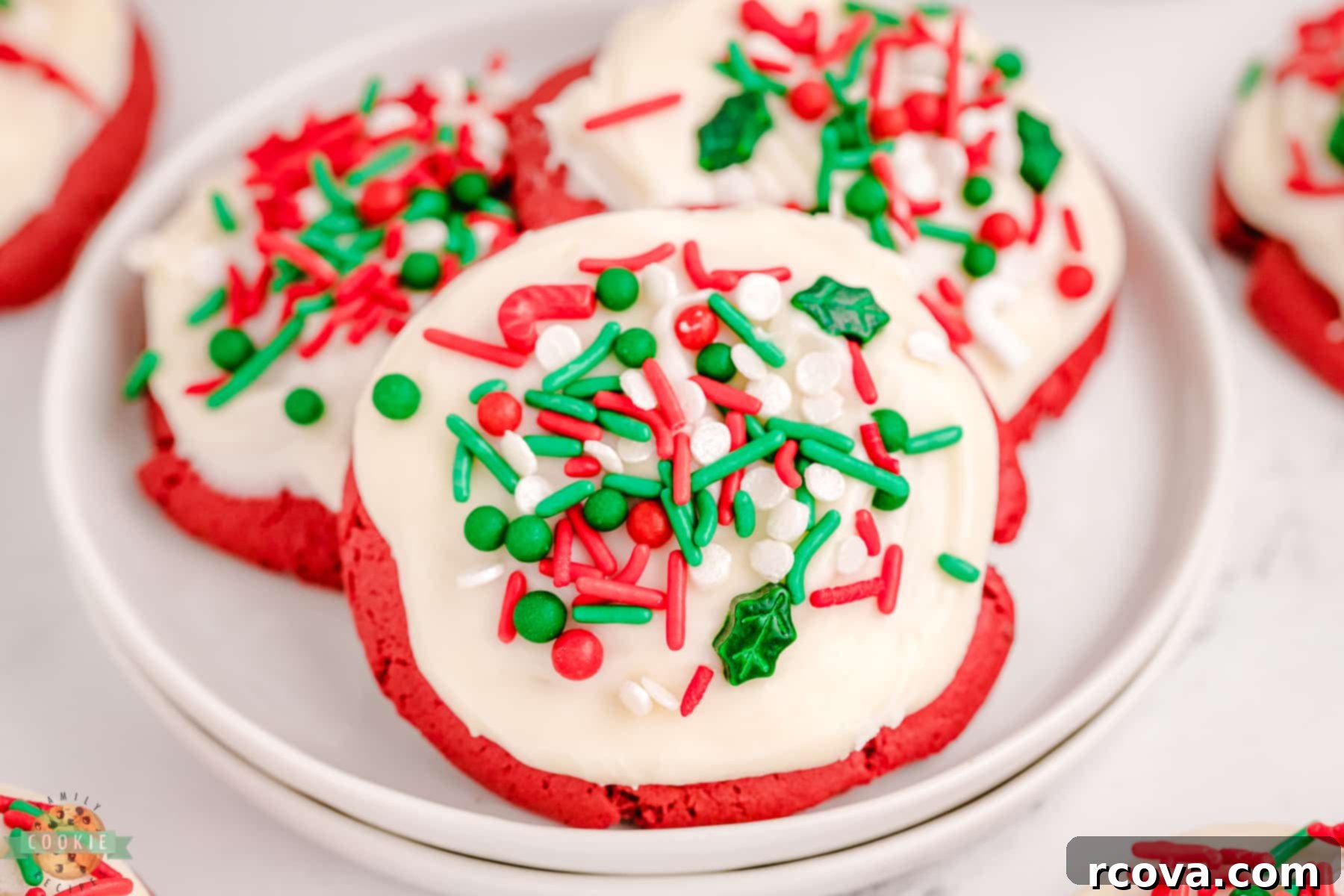 Crimson Velvet Holiday Treats 3 Close-up of frosted red velvet holiday cookies on a rustic wooden surface, decorated with colorful Christmas sprinkles