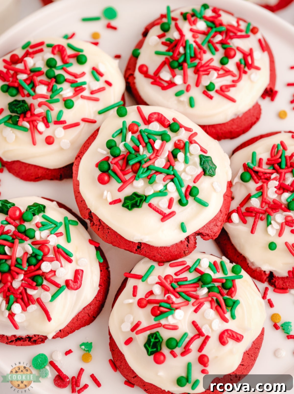 Crimson Velvet Holiday Treats 5 Close-up of two red velvet cookies topped with generous swirls of cream cheese icing and colorful sprinkles, ready to be enjoyed