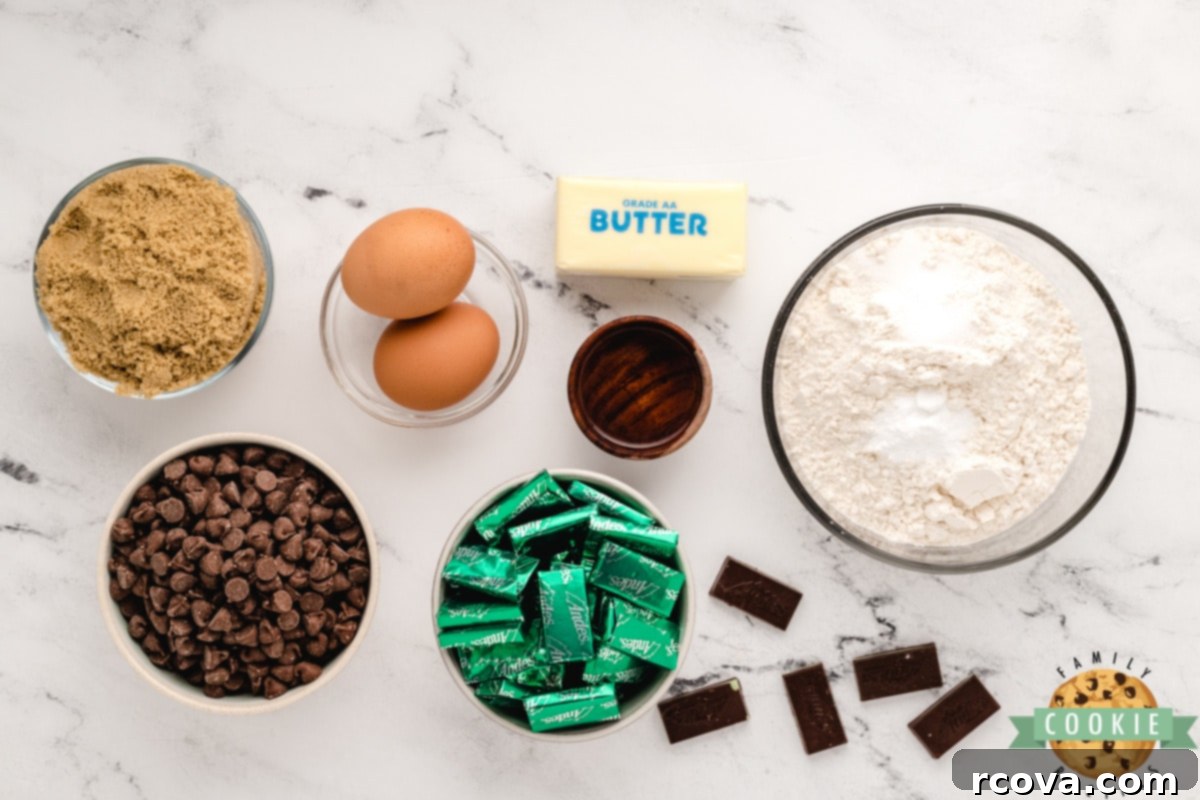 Decadent Andes Mint Chocolate Cookies 3 Ingredients for Andes Mint Chocolate Cookies arranged on a baking sheet, including butter, brown sugar, chocolate chips, eggs, flour, and Andes mints.