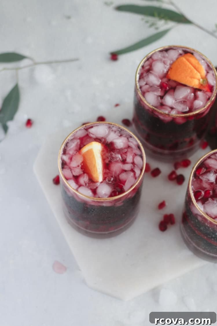Garnet Pinot Punch 2 Pomegranate Pinot Punch, a festive red cocktail garnished with orange slices and pomegranate seeds.