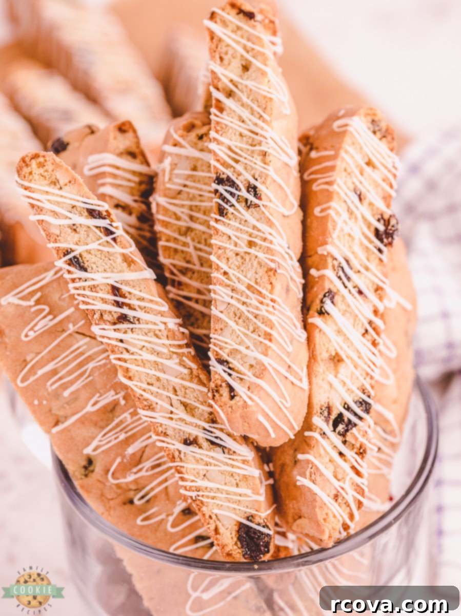 Double-Baked Cherry Delights 2 White chocolate drizzled cherry almond biscotti, elegantly presented on a plate