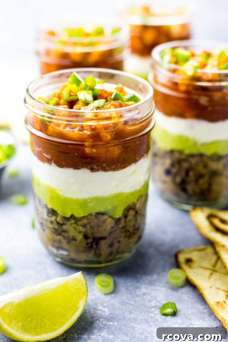 Party-Perfect Stacked Buffalo Chicken Dip Jars 5 A person dipping a tortilla chip into a Mini Buffalo Chicken Salsa Dip Jar, showcasing the layers.