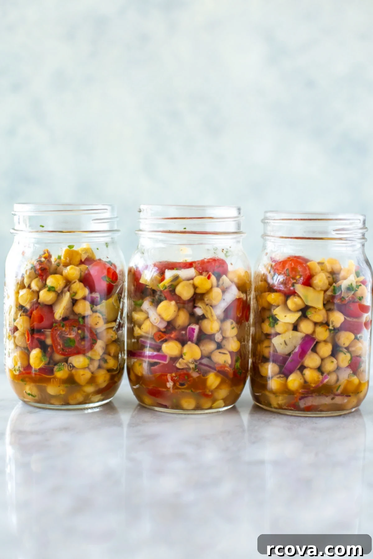 Effortless Mediterranean Chickpea Salad 2 Three mason jars, each with a serving of vibrant Mediterranean chickpea salad, ready for healthy lunches.
