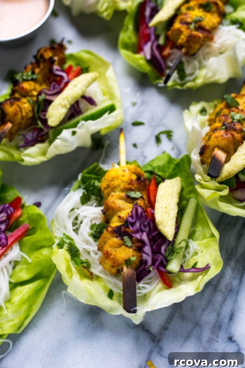 Crisp Chicken Satay Lettuce Wraps 5 A vibrant platter of individual Chicken Satay Lettuce Wraps filled with colorful vegetables, vermicelli, and grilled chicken, ready for serving.