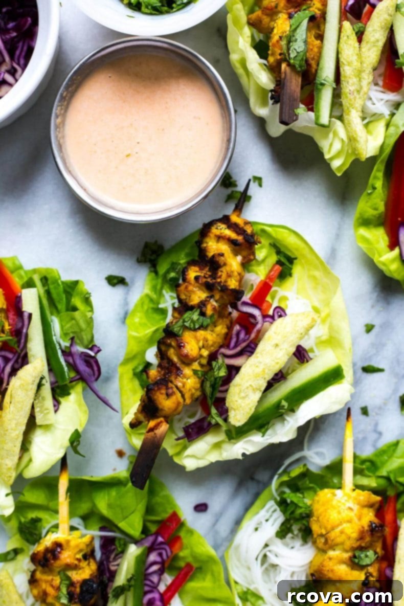 Crisp Chicken Satay Lettuce Wraps 7 Overhead view of several Chicken Satay Lettuce Wraps arranged on a white serving dish, garnished with fresh cilantro.