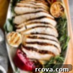 Perfect Air Fryer Turkey Breast 7 slices of turkey decoratively displayed on an oval serving tray with a garlic head, charred lemon and fresh sage, thyme and rosemary.