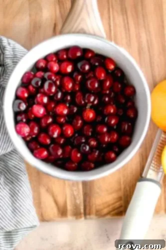 Honey-Kissed Orange Cranberry Sauce 5 Cranberries simmering in a pot with orange slices.