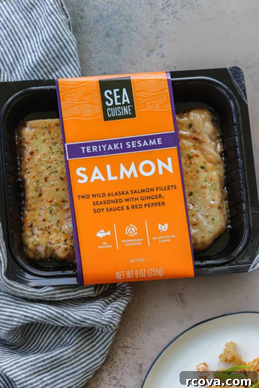 Effortless One-Pan Salmon Fried Rice 3 A person adding flaked salmon to a skillet of fried rice with vegetables and scrambled eggs.