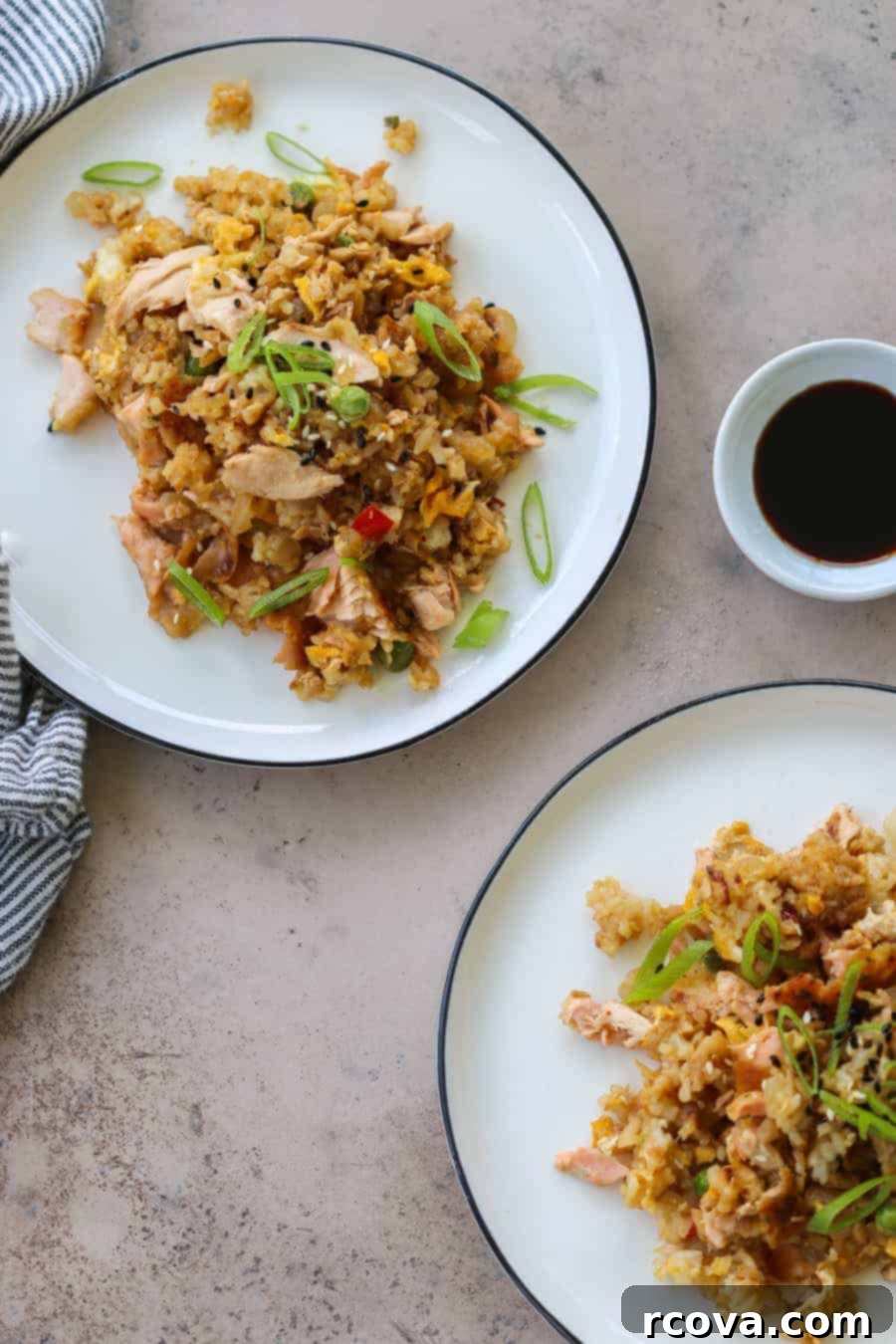 Effortless One-Pan Salmon Fried Rice 6 A serving of salmon fried rice with green onions on a white plate, with a wooden spoon.