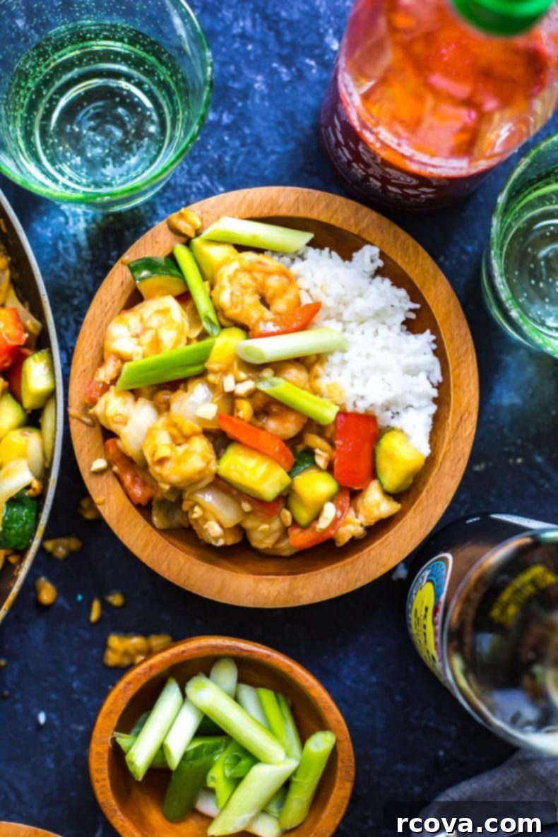 This 30-Minute Kung Pao Shrimp is a delicious, quick and easy stir fry that's perfect for getting dinner on the table quickly! Switch up the veggies to use whatever's leftover in your fridge! A vibrant close-up of a bowl of 30-Minute Kung Pao Shrimp with Jasmine rice, garnished with fresh green onions and crunchy peanuts, ready to be enjoyed.