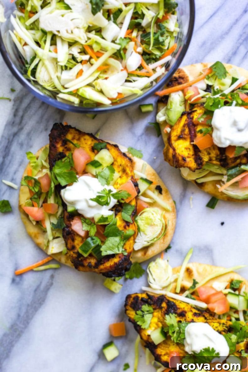 Tandoori Chicken Naan Burgers 6 A vibrant Tandoori Chicken Naan Burger with fresh vegetables and creamy sauce, presented on a wooden board.