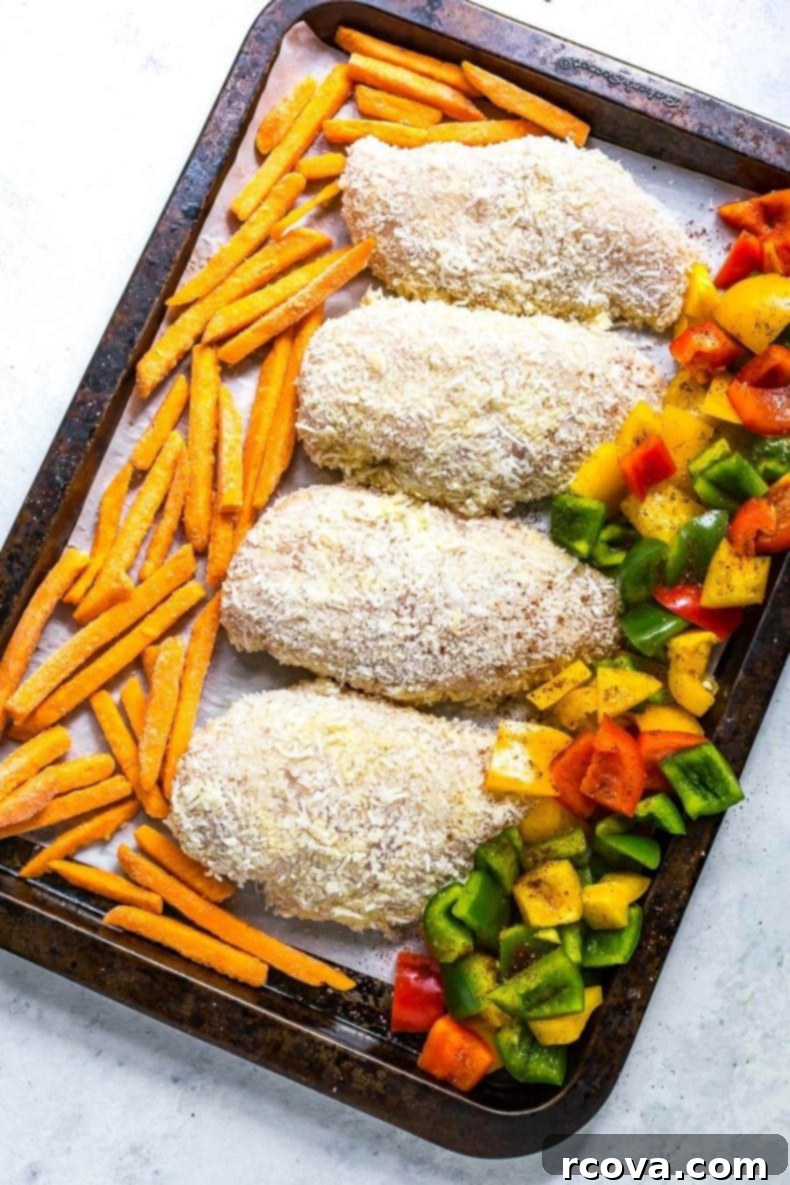 Golden Crispy Coconut Chicken Sheet Pan Dinner 4 Close-up of coconut crusted chicken on a sheet pan with roasted bell peppers.