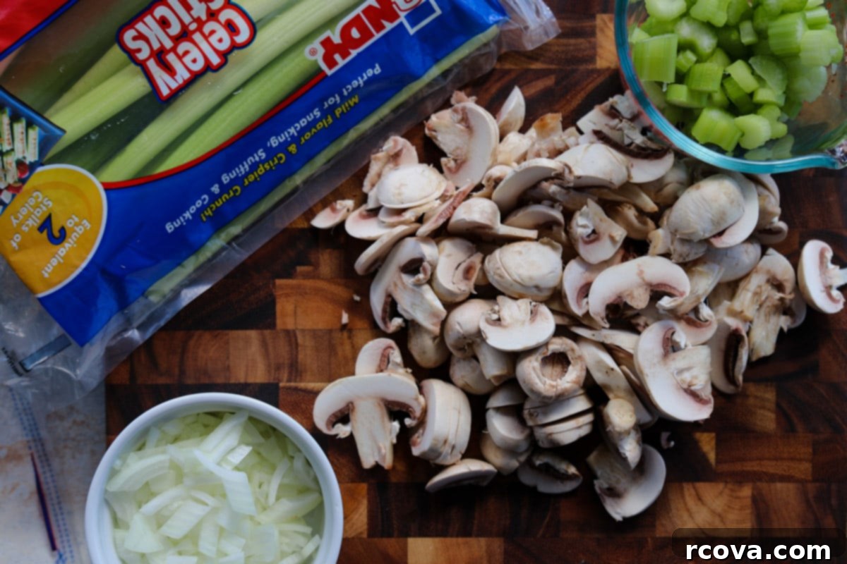 Stress-Free Slow Cooker Mushroom Stuffing 3 Fresh ingredients laid out on a wooden cutting board, including bread cubes, celery, onion, and mushrooms, ready for slow cooker stuffing preparation.