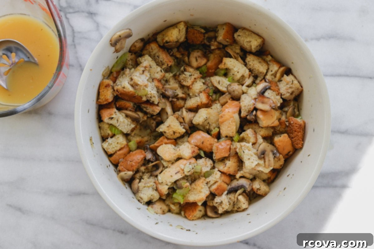 Stress-Free Slow Cooker Mushroom Stuffing 7 A large mixing bowl containing dried bread cubes, sautéed vegetables, and liquid, ready to be combined for slow cooker stuffing.