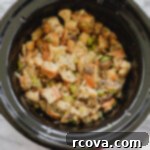 Stress-Free Slow Cooker Mushroom Stuffing 9 A close-up shot of slow cooker stuffing, garnished with fresh herbs, in a ceramic pot.