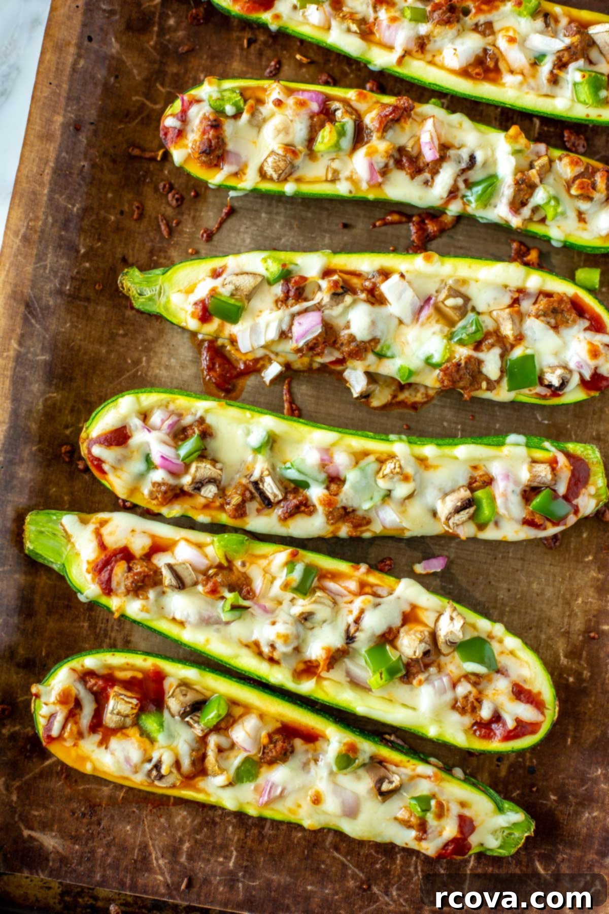Quick Zucchini Pizza Boats 7 A tantalizing close-up shot of several zucchini pizza boats arranged neatly on a baking sheet, showcasing their rich, melted cheese and colorful toppings.