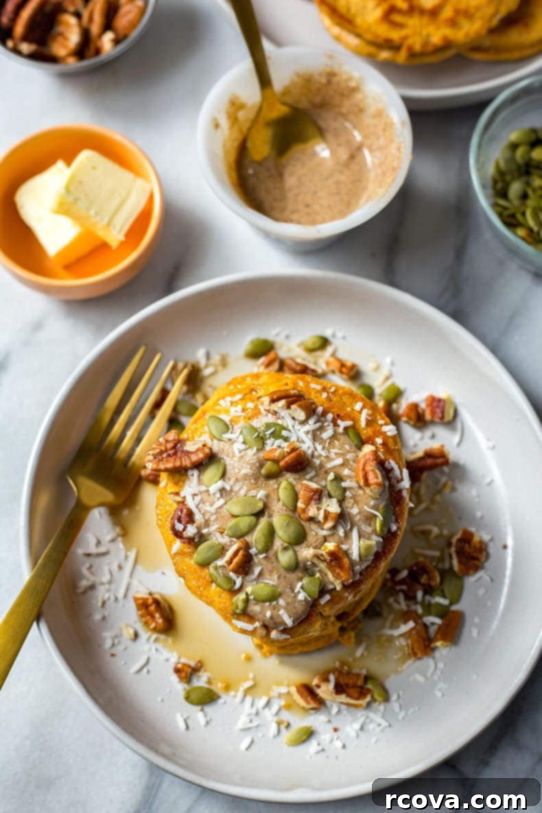 Easy 5-Ingredient Pumpkin Protein Pancakes 9 Close-up of a stack of pumpkin protein pancakes, cut open to show the fluffy interior, with a fork and a drizzle of maple syrup.