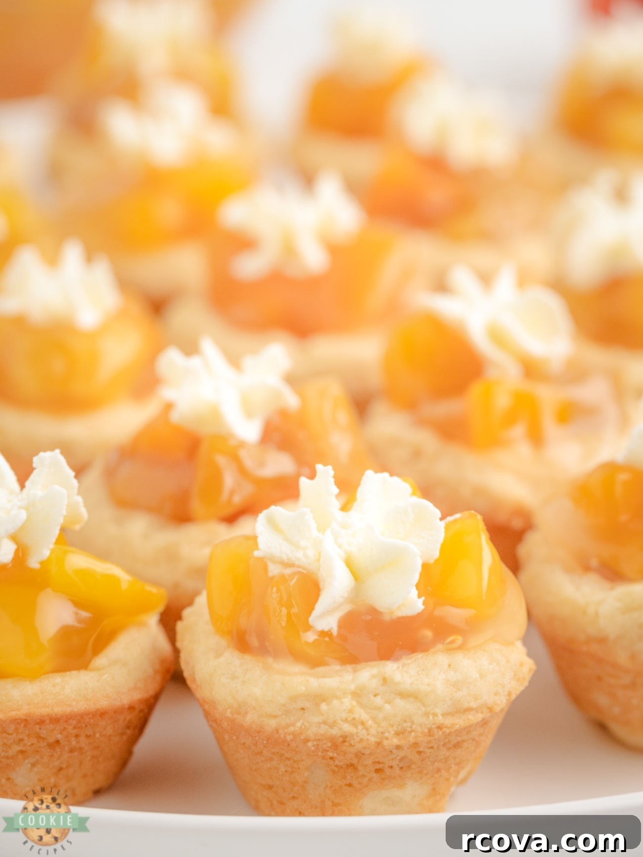 Peachy Dream Cookies 3 Close-up of baked peaches and cream cookies on a white plate, showcasing the golden cookie and rich peach filling with whipped cream.