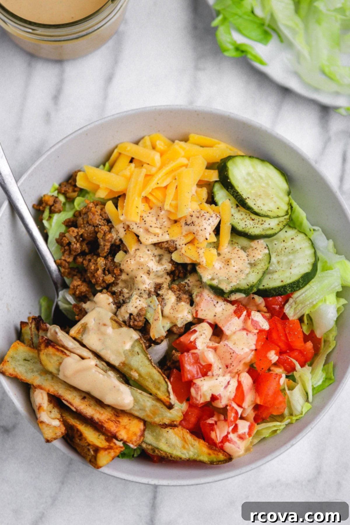 Signature Drizzle Cheesy Burger Bowls 2 loaded burger bowls with iceberg, ground beef, cheddar cheese, French fries, pickles, drizzled in a secret sauce