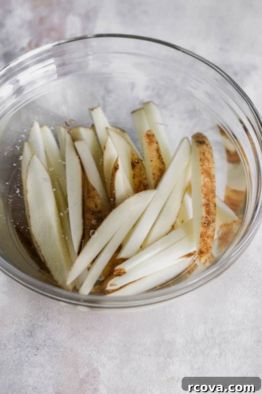Homemade Air Fryer Fries: Perfectly Crispy 4 Sliced Russet potatoes soaking in cold water to remove starch.