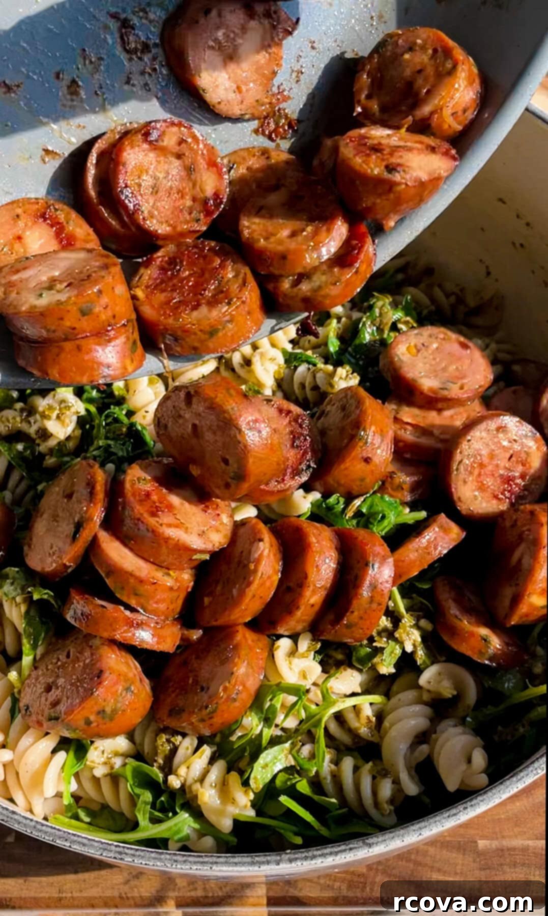Easy Pesto Chicken Sausage Pasta 6 adding sliced chicken sausage to pasta