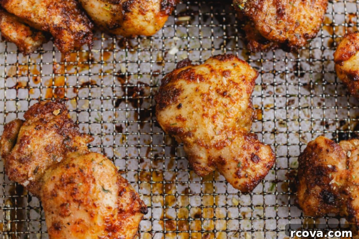Crispy Air Fryer Chicken Thighs 5 Beautifully grilled chicken thighs resting on a wire rack, allowing excess juices to drip away.