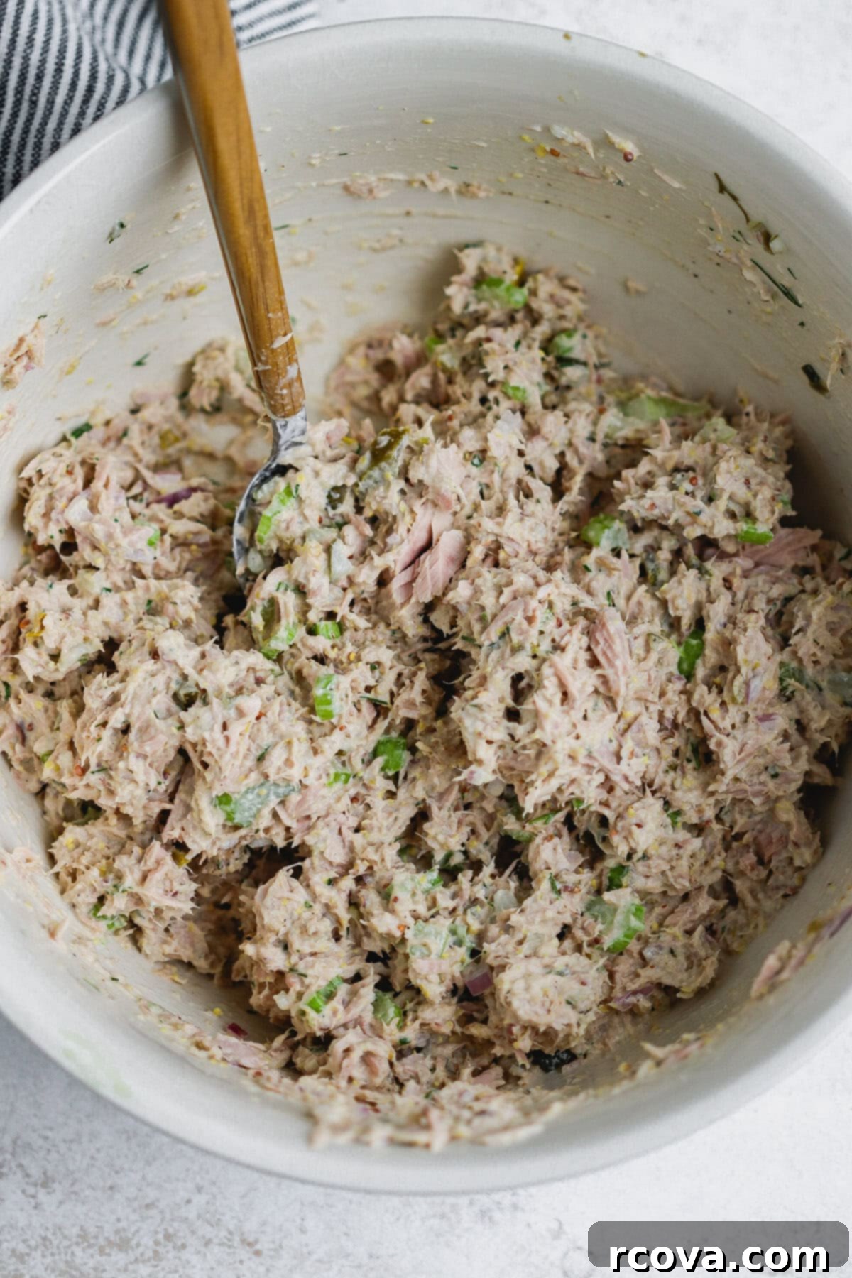Jalapeño Zing Tuna Melt 4 A bowl of creamy tuna salad with a wooden spoon, showcasing the mix of tuna, vegetables, and dressing.