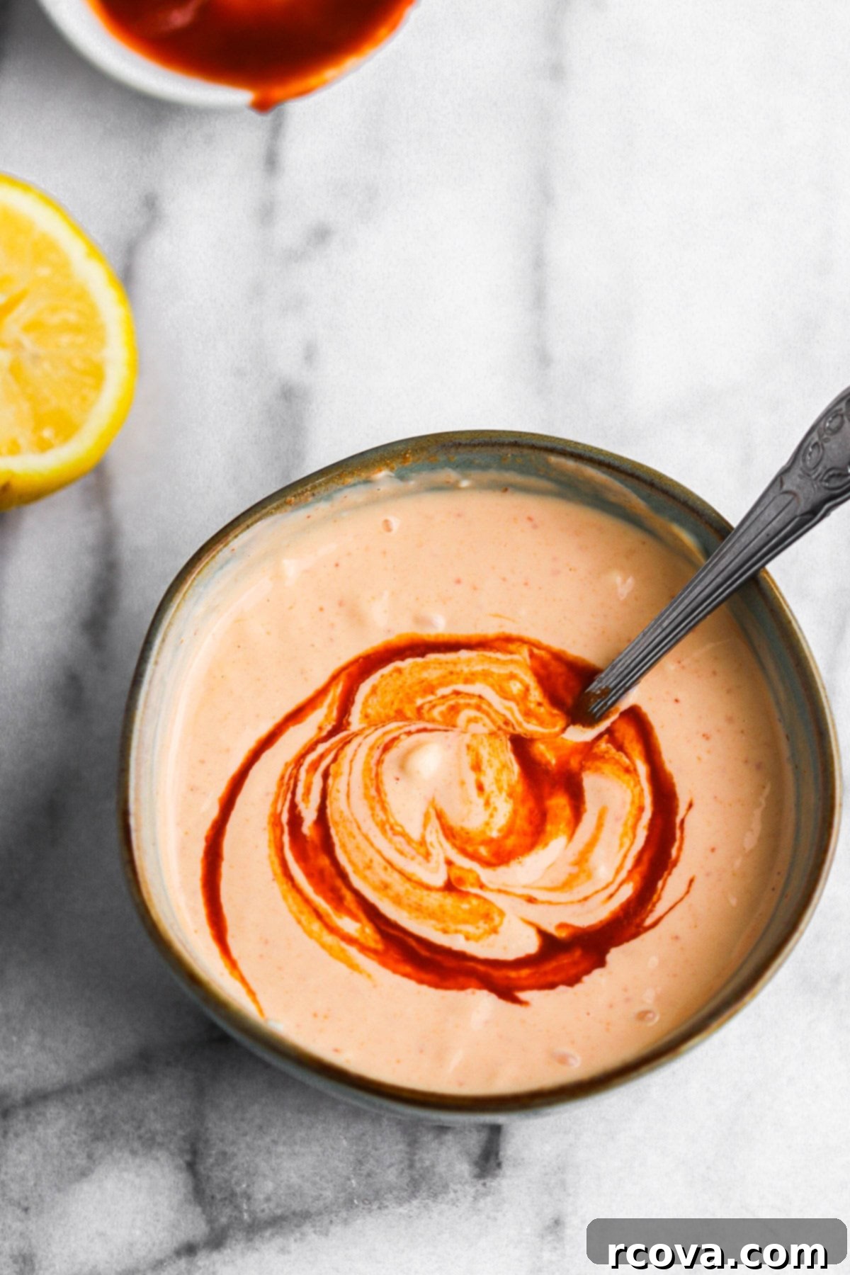 Tangy Sriracha Mayo 4 Ingredients for Sriracha Mayo: a bowl of mayonnaise, a bottle of Sriracha sauce, and a fresh lemon half.