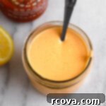 Tangy Sriracha Mayo 7 Overhead shot of creamy sriracha mayo in a small white bowl with a spoon.