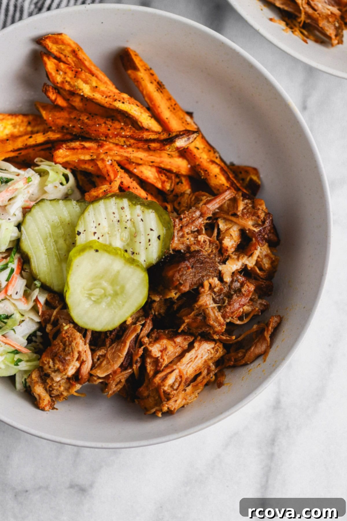 Effortless Sugar-Free Slow Cooker Pulled Pork 7 Close-up of a pulled pork sandwich with coleslaw and pickles.