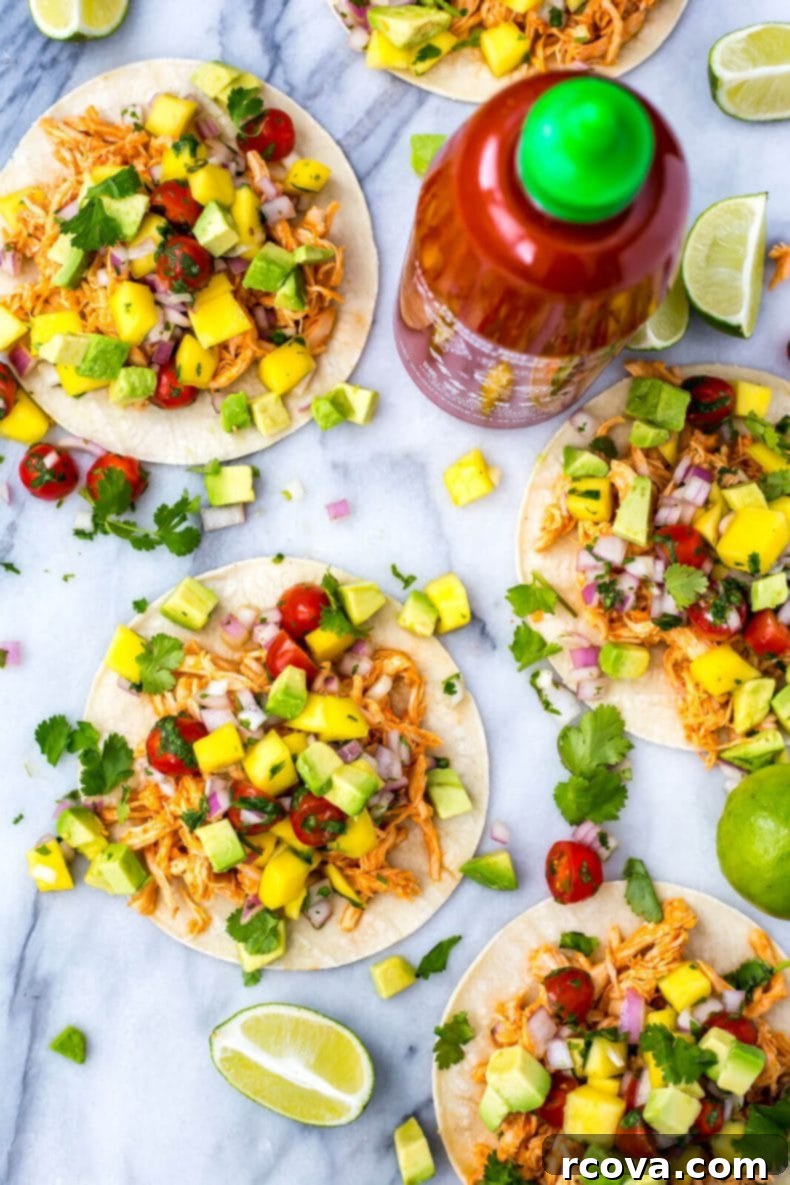Spicy Instant Pot Sriracha Chicken Tacos 2 Instant Pot Sriracha Chicken Tacos served with fresh mango and avocado salsa on a wooden board.