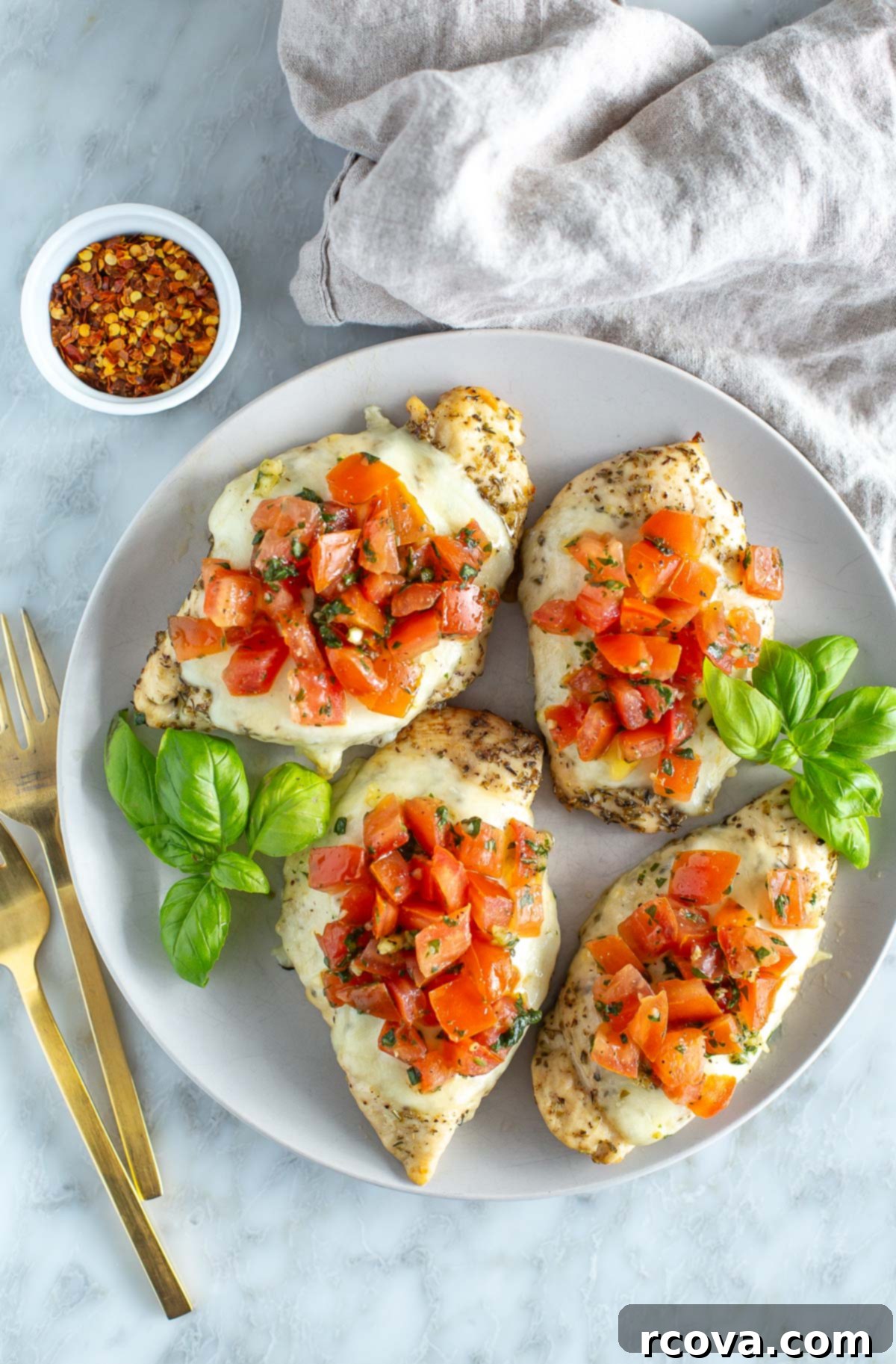 One-Pan Bruschetta Chicken Bake 2 Three pieces of chicken with tomatoes and basil on a plate