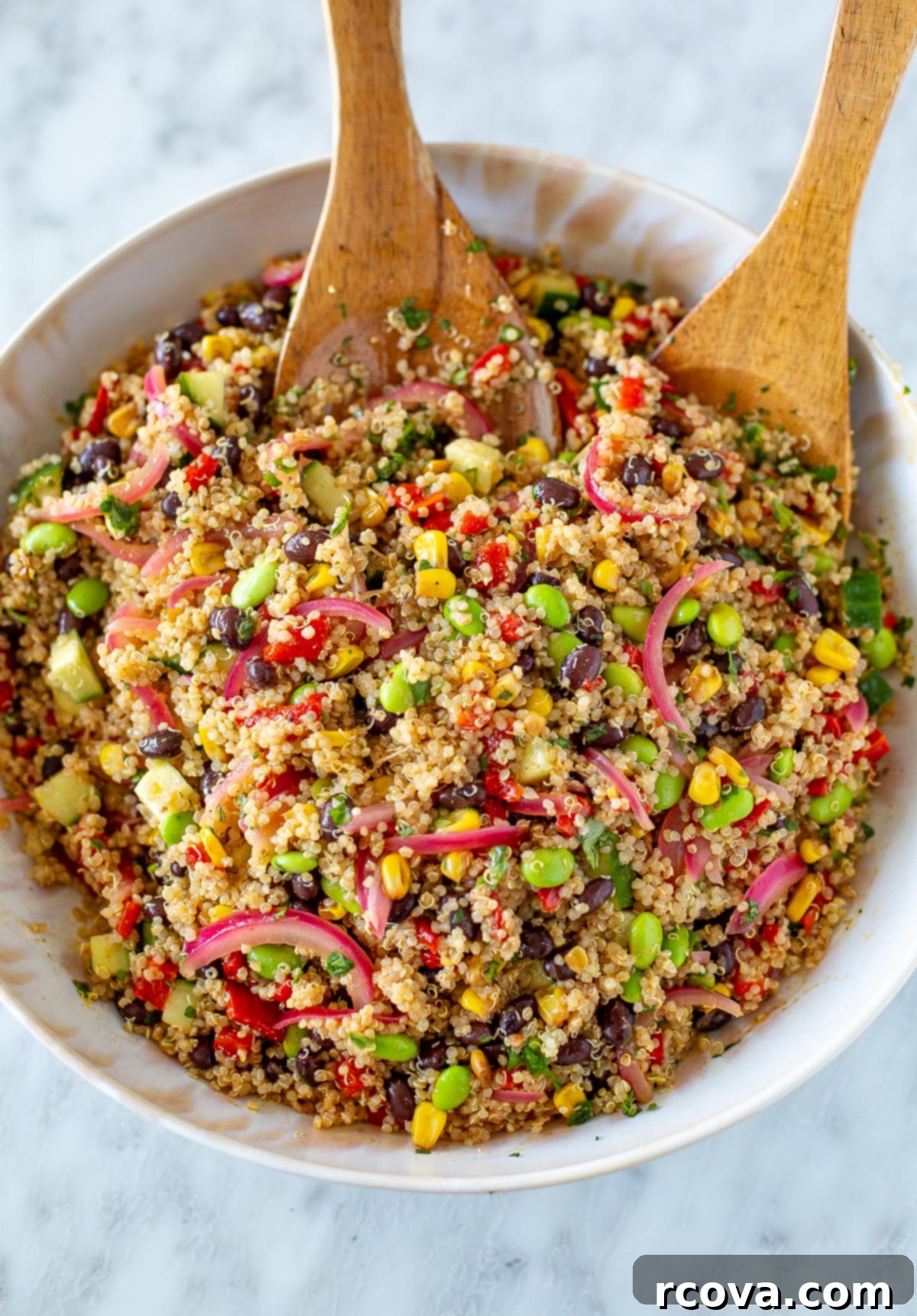 40+ Easy and Healthy Meal Prep Lunches for Work 16 Overhead shot of quinoa salad with two wooden spoons tossing the salad, a protein-packed vegan dish.
