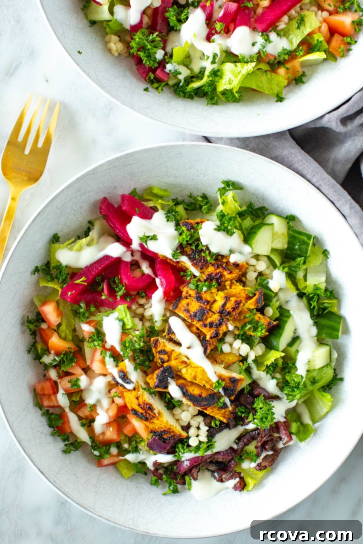 40+ Easy and Healthy Meal Prep Lunches for Work 36 A close-up of a chicken shawarma bowl topped with garlic sauce and fresh herbs.